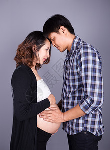 年轻夫妇母亲怀孕父快乐身穿灰墙背景图片