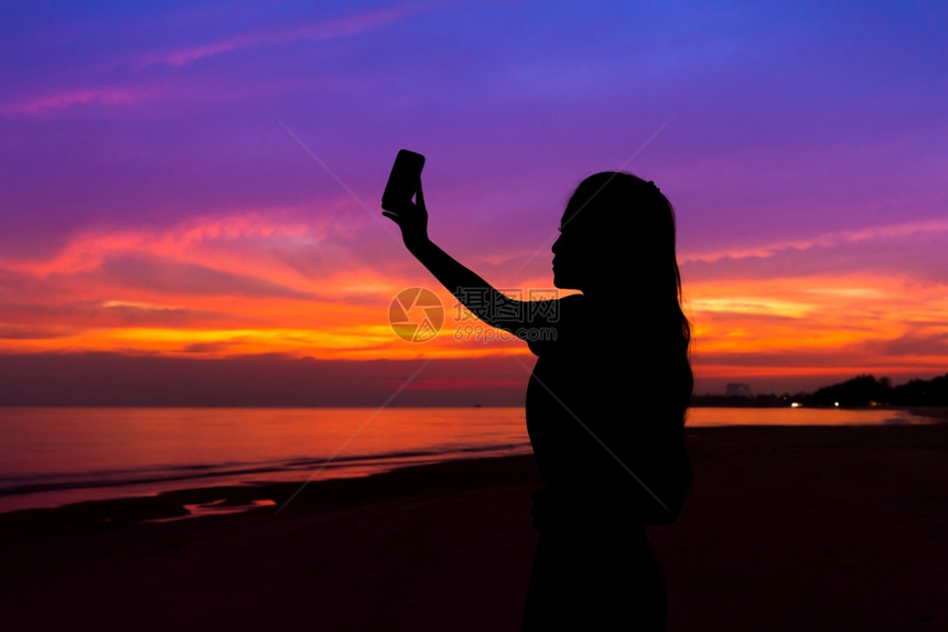 妇女用手机在海滨拍摄日落照片的休丽月光图片