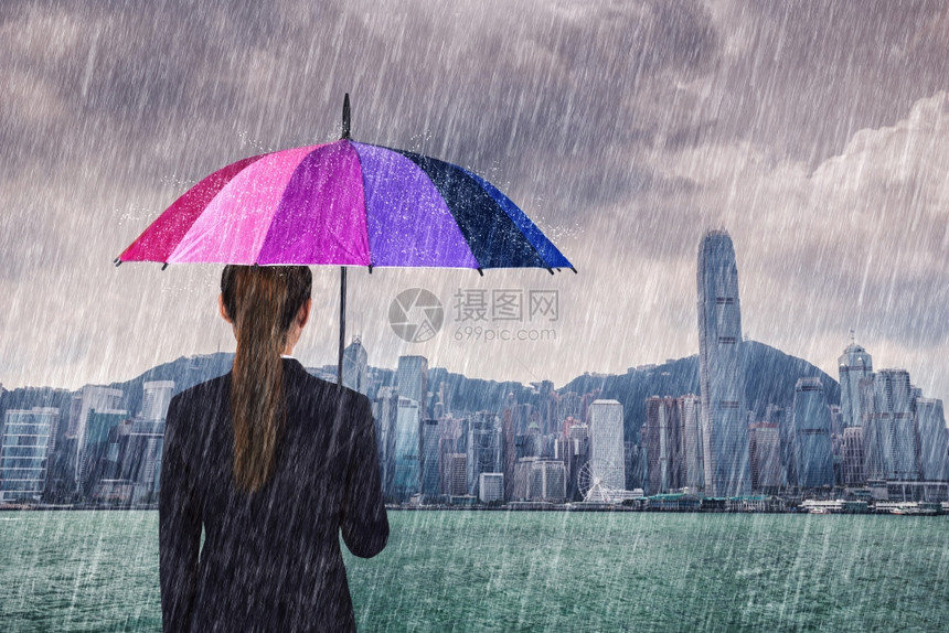 在香港维多利亚港举行多雨雨伞的女商人图片