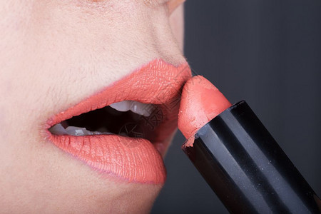 近身女人在嘴唇上涂橙色口红图片