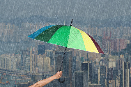 手拿五彩雨伞以香港城为背景图片