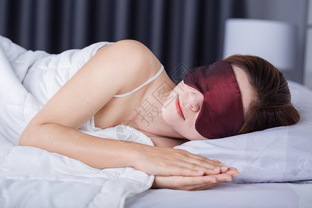 睡在床上并戴眼罩的美丽妇女图片