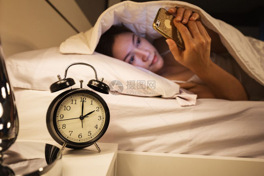 时钟2点女人睡在白毯下卧室的床上图片