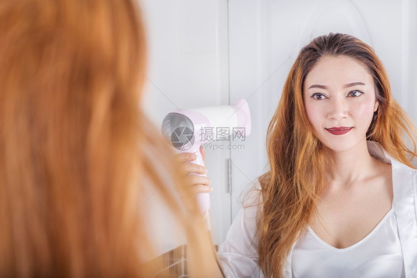 女人看着镜子里的女人在浴室里擦头发图片
