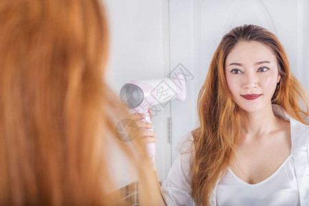 女人看着镜子里的女人在浴室里擦头发图片