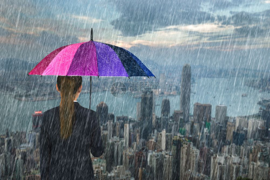 香港市背景雨下拥有多彩伞的女商人图片