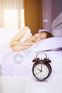 桌子上的闹钟和睡在卧室床上的女人图片