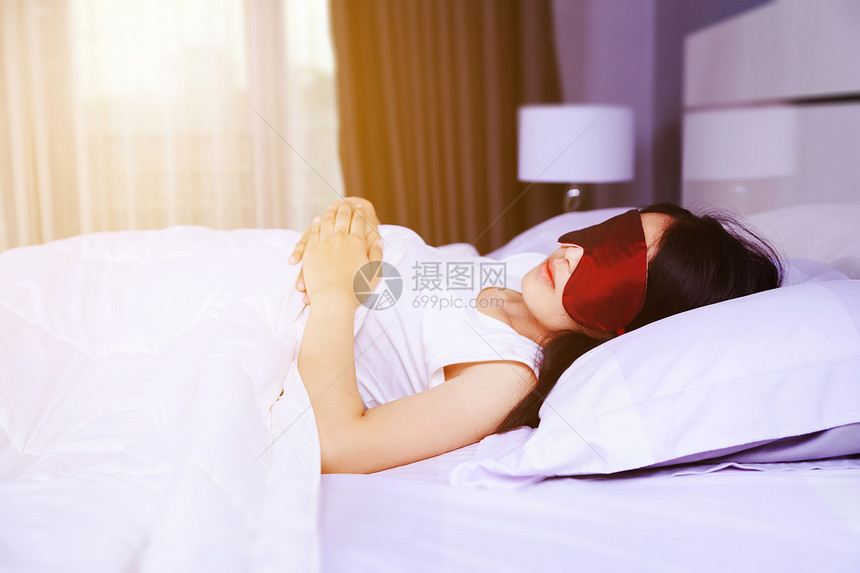 妇女睡在卧室的床上时戴面罩睡在床上图片