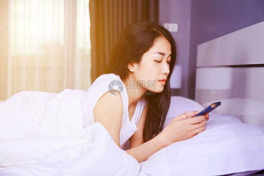 女人用手机在卧室的床上用手机图片