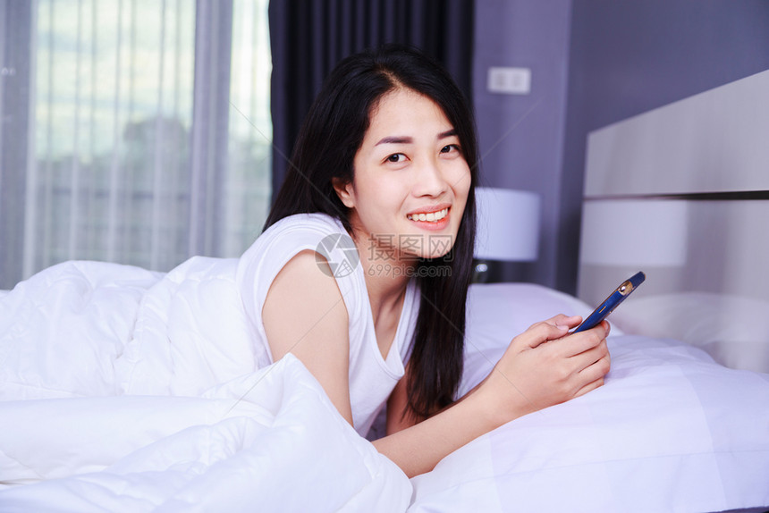 女人用手机在卧室的床上用手机图片