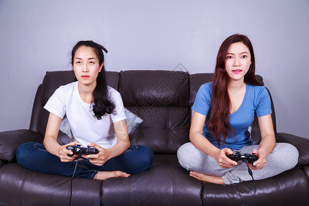 两名女青年在家中客厅沙发上玩游戏图片