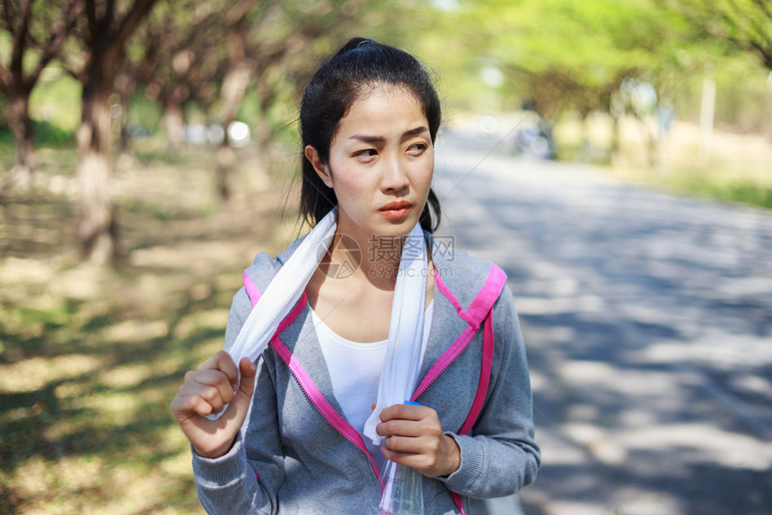 在公园户外运动后带白毛巾的年轻运动女青者休息图片