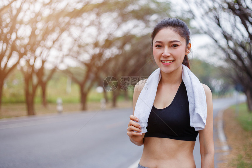 在公园户外运动后带白毛巾的年轻运动女青者休息图片