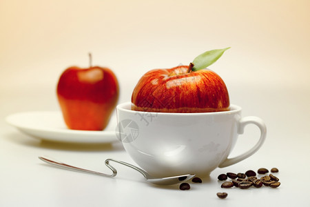 乌饭叶茶杯碟勺子和咖啡豆中的苹果背景