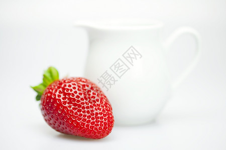 近视图白纸上的草莓和奶罐背景图片