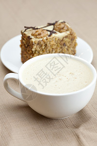 杯卡布奇诺咖啡一块蛋糕坚果在盘子上图片