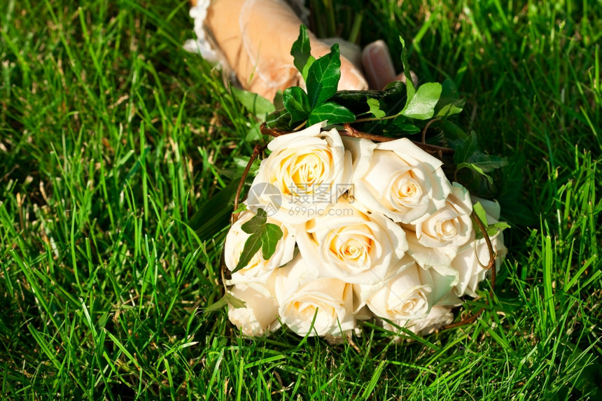 新娘手放在绿草上的新娘手花束图片