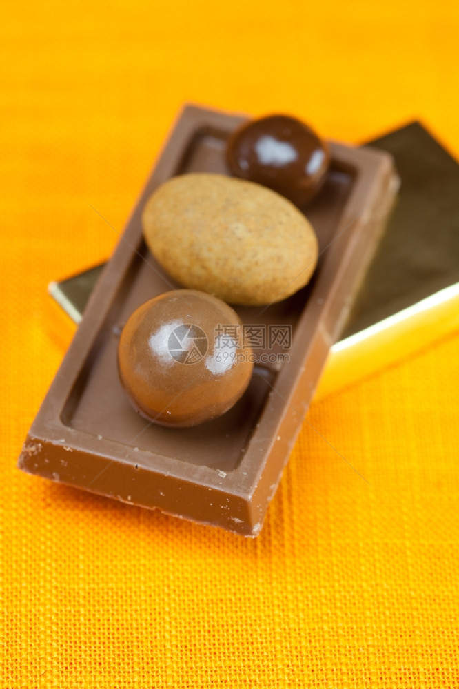 橙色织物上的巧克力条和糖果图片