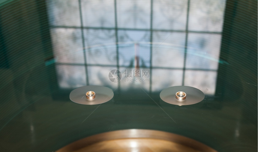 玻璃桌上美丽的彩色玻璃和结婚戒指图片