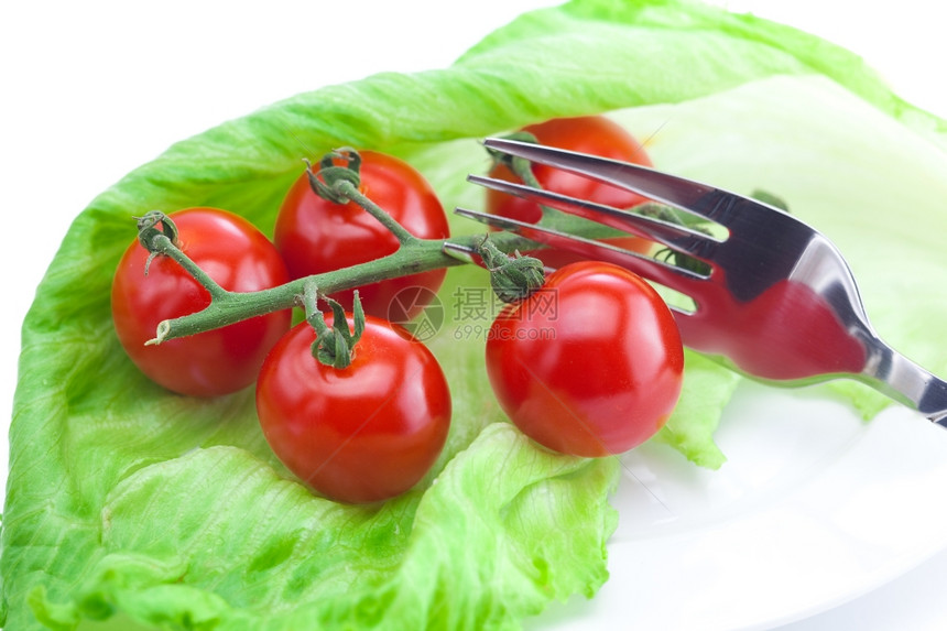 番茄和生菜叉子在盘上白隔绝图片