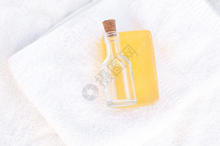 白毛巾上的肥皂和玻璃瓶图片