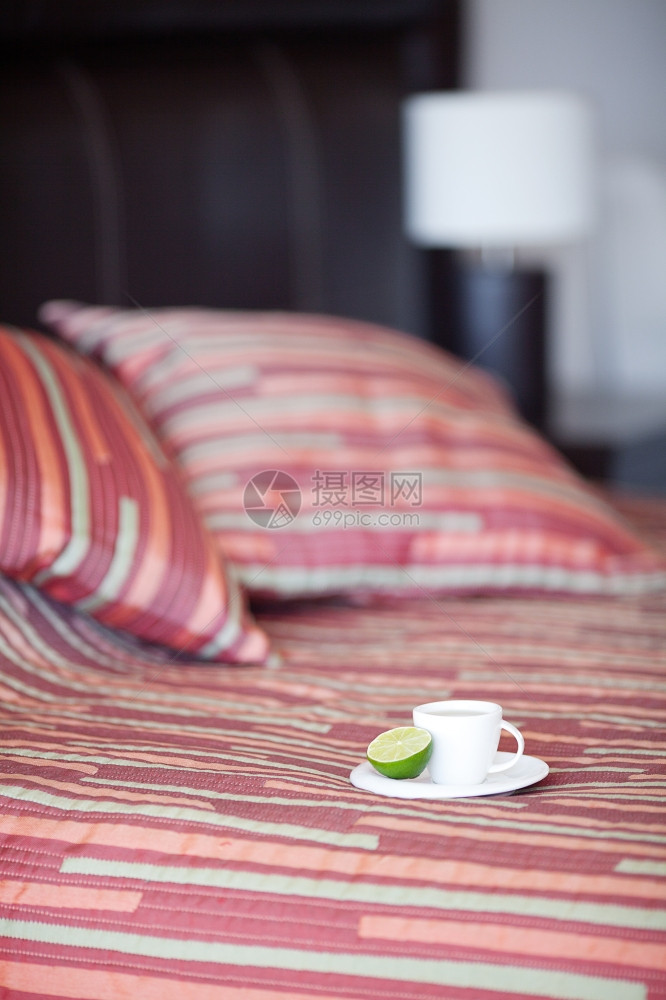 床铺上有两个枕头毯子上还有一杯茶图片