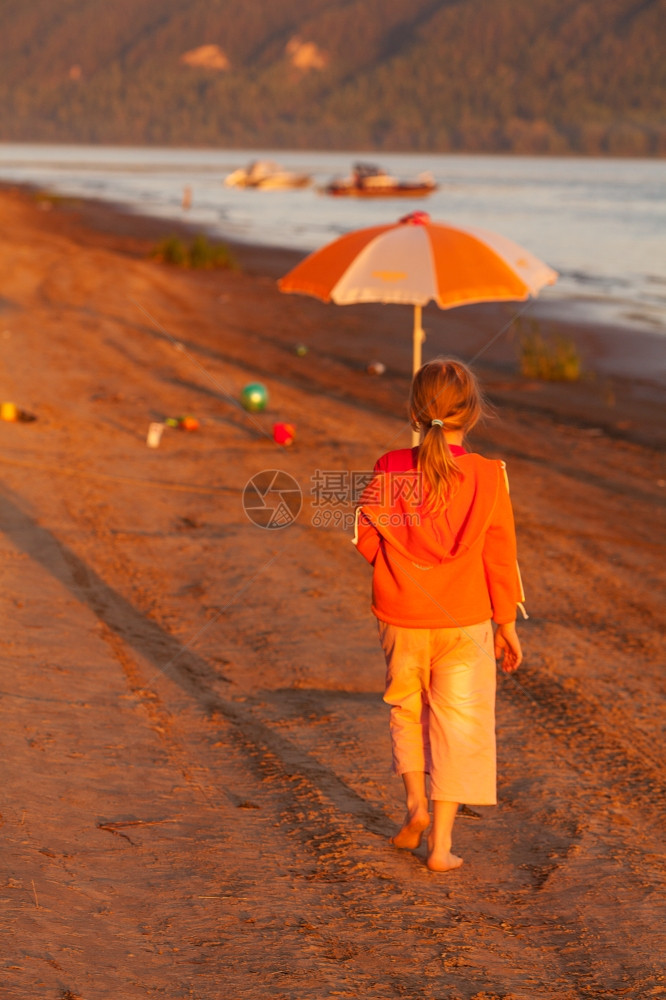 小女孩在阳光照耀的海滩上奔跑图片