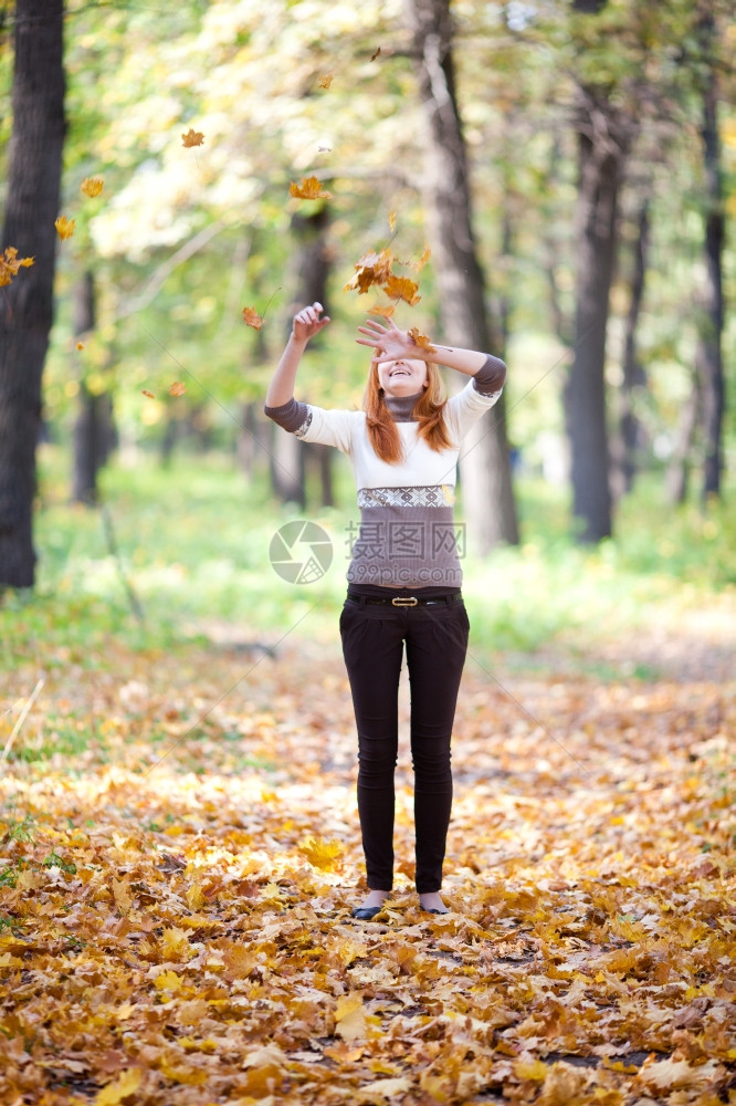 年轻红发青少扔叶子在森林中的女人图片