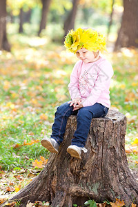小女孩戴着花环坐在树桩上图片