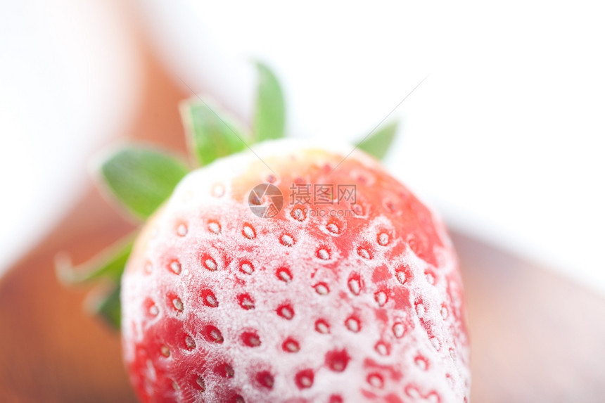 用木勺冷冻的大红草莓孤立在白色上图片