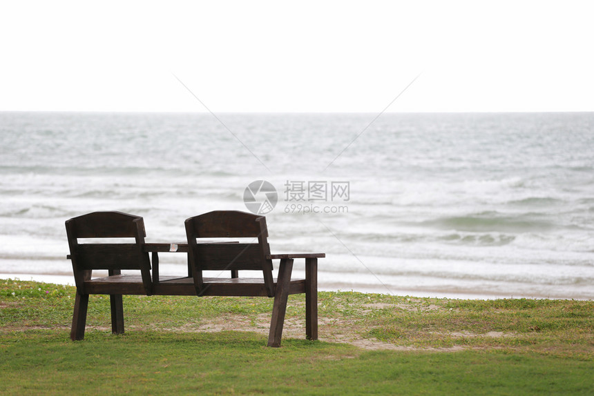 草坪上的旧空木椅草坪海滩和洋背景上的旧空木椅子图片
