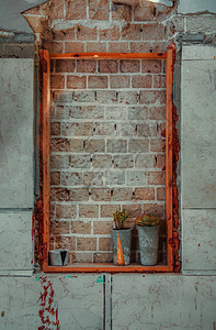 在废弃的建筑物中用红砖封住的窗户放在台上的两座陶瓷工厂图片