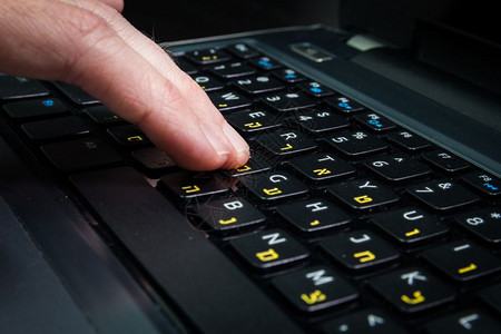 在键盘上打字的人用希伯来语和英字母打笔记本键盘关闭dark大气层图片