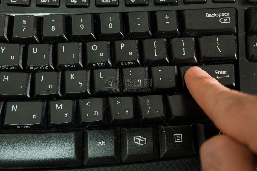 男人在无线键盘上打字用希伯来语和英字母打按Enter键顶级视图图片