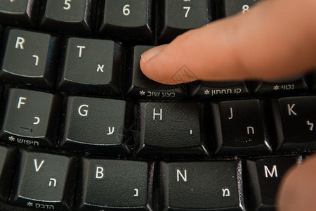 男人在无线键盘上打字用希伯来语和英字母打按Redo钮顶级视图图片