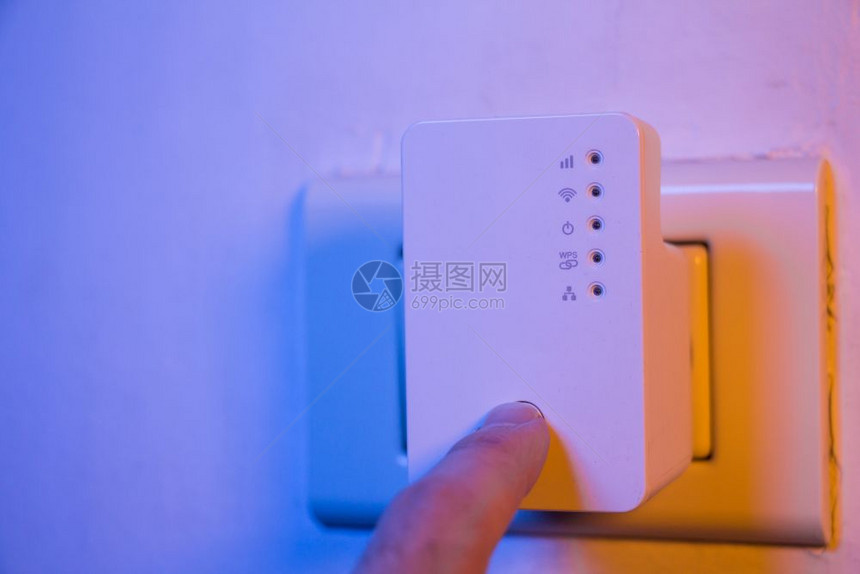 男人用他的手指按WPS钮在墙上的电插座中WiFi继器上该设备有助于扩展家庭或办公室的无线网络图片