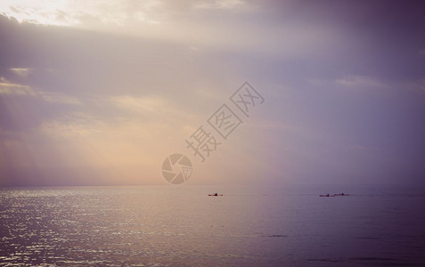 日落时有三只独木舟在海上航行图片