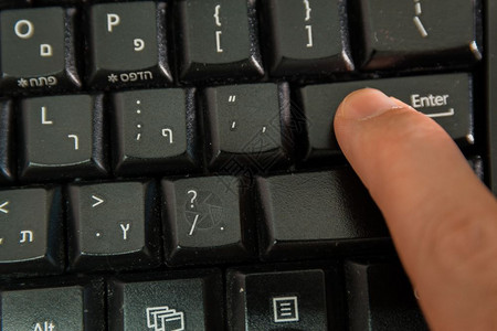 男人在无线键盘上打字用希伯来语和英字母打按Enter键顶级视图图片
