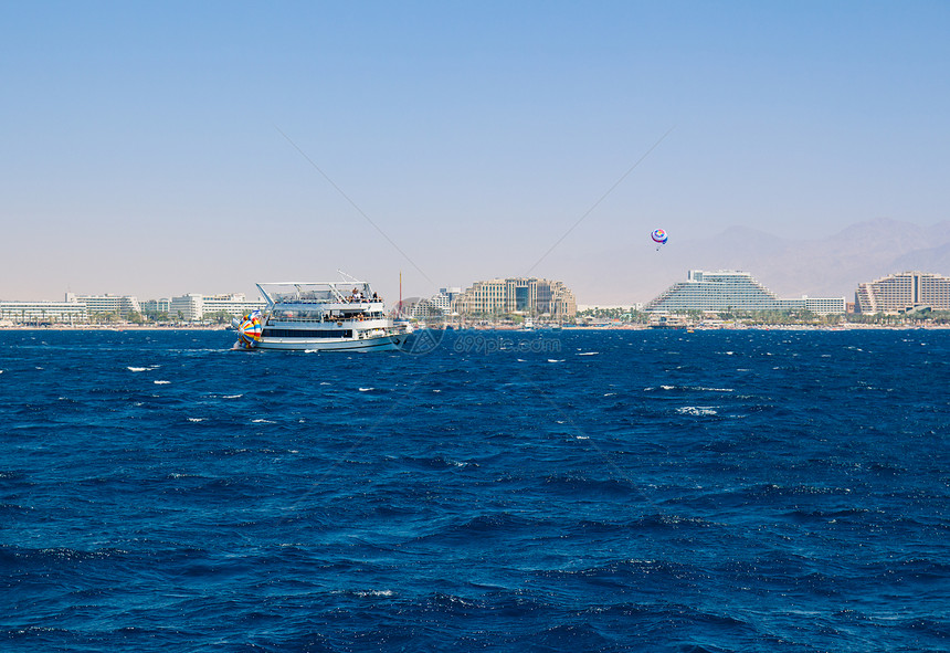 在红海的游艇航行背景是伊拉特的旅馆地带图片