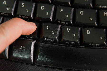 男人在无线键盘上打字用希伯来语和英字母打按下剪切钮顶级视图图片