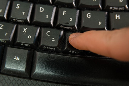 男人在无线键盘上打字用希伯来语和英字母打按粘贴钮顶级视图图片