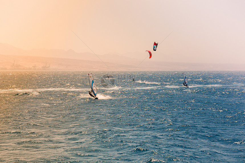 风帆在红海航行以色列伊拉特海滩附近亮橙色光从左边的太阳中射出图片