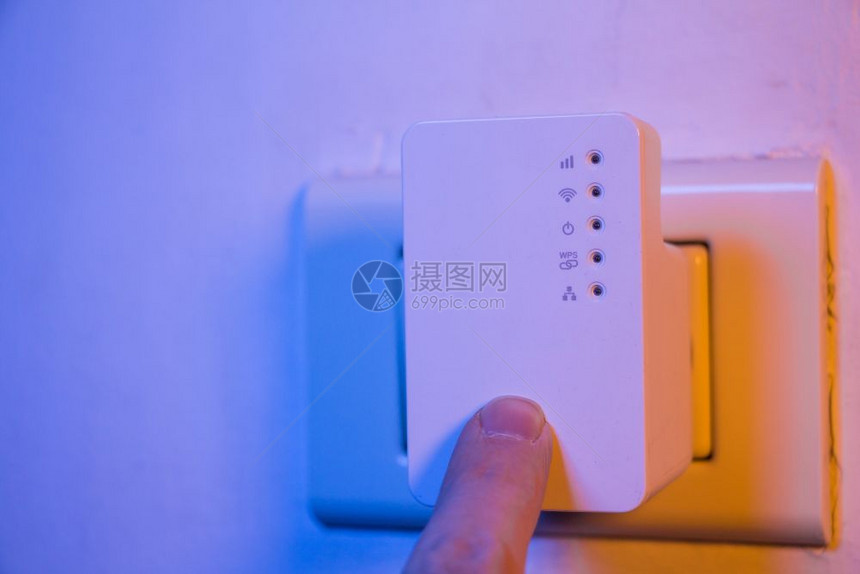 男人用他的手指按WPS钮在墙上的电插座中WiFi继器上该设备有助于扩展家庭或办公室的无线网络图片