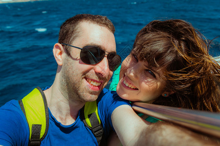 快乐的情侣在船上航行带着智能手机或相自拍图片