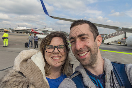 情侣在飞机外面拿着智能手机玩自拍背景图片