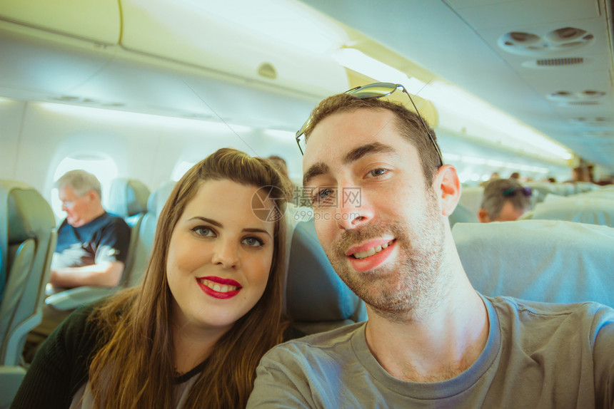 情侣在飞机上带着智能手机玩自拍图片