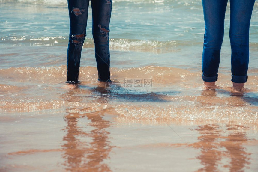 身穿蓝色牛仔裤的妇女站在海岸水中图片