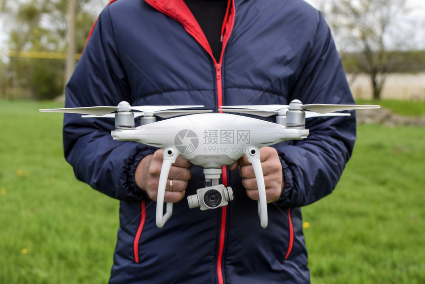 俄罗斯克拉诺达尔2017年5月日一个人手里拿着石匠正在准备一架白色无人机进行飞幻影一个人手里拿着石匠一只白色无人机正在准备飞行图片