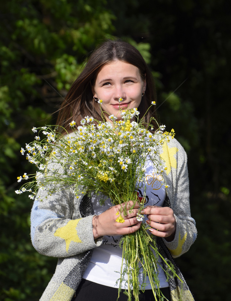 年轻美丽的女孩带着一束甘菊花个女人在大麦田里年轻美丽的女人站在森林里拿着一束甘菊花图片