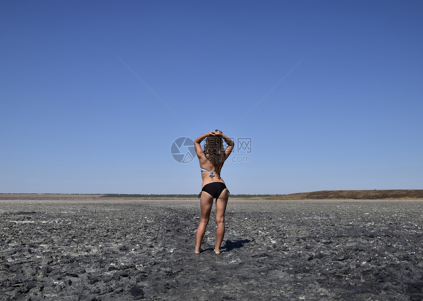 站在盐湖干涸湖底的女孩穿着泳衣的黑发女子走在一个充满盐和泥的干涸湖底古老的干涸湖泊站在盐湖干涸湖底的女孩图片